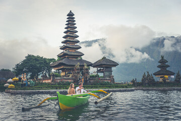 Happy young couple spending time at the ulun datu bratan temple in Bali, cruising on a catamaran
