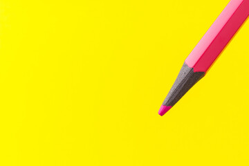 Colored pencil close-up with selective focus on the stylus and a blurred yellow background. Copy space