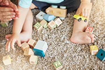Closeup of baby learning with toys, block puzzle and train to help hand eye coordination on floor...