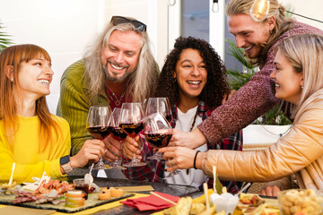 Happy multiracial friends cheering glasses drinks in a bar restaurant-Smiling young people enjoying happy hour drinking wine-Teenagers celebrating party together- Beverage Lifestyle concept 