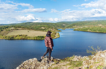 Fototapeta na wymiar Young woman walking outdoor in the nature high above a lake with stunning view . Pchelina lake in Bulgaria .Scenic landscape 