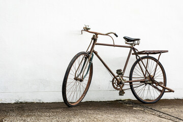 Naklejka na ściany i meble Vintage old bike leaning against white wall background