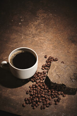 Cup of freshly brewed roasted coffee beans on brown background