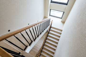 stairs made of tiles in a new house. metal black railing with wooden handrails