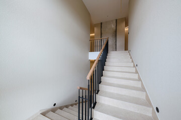 stairs made of tiles in a new house. metal black railing with wooden handrails