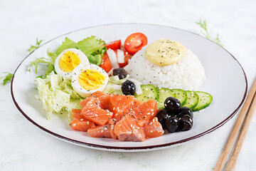 Fresh organic salmon salad with rice, boiled egg, tomatoes, cucumber and black olives. Fast and healthy food, lunch, nutrition concept.