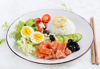 Fresh organic salmon salad with rice, boiled egg, tomatoes, cucumber and black olives. Fast and healthy food, lunch, nutrition concept.