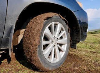 Close up of an off-road car's tyre covered with mud. Outdoor, adventure and travel concept. High quality photo
