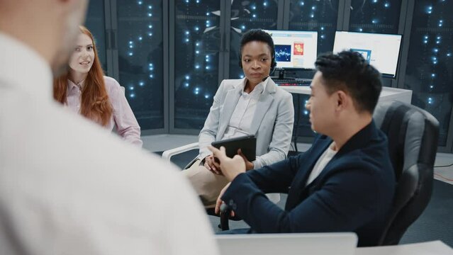 Close up happy people on business meeting in data center. Multi-ethnic experienced staff of IT workers communicating about business plans. Cyber security office. Server racks. Teamwork.