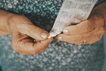 Close up of old woman hands taking pills medicine. Health and unhealthy mature elderly people using pharmacy treatment to prevent bad condition diseases. Concept of aged people taking care with pills