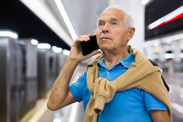 Senior man with phone in metro station