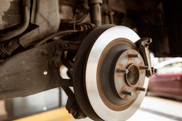 Car disc brake system. Car suspension in process of new tire replacement at garage workshop. Car...