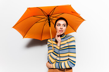 dreamy woman in striped turtleneck standing under orange umbrella on white.