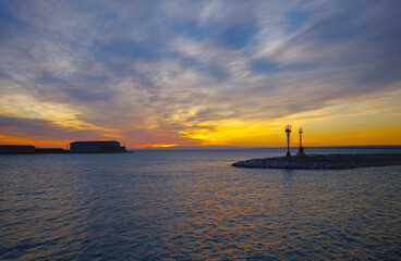 Sunrise in the port of Termoli, in the foreground the silhouette of the lighthouse and flags. Molise, Adriatic sea