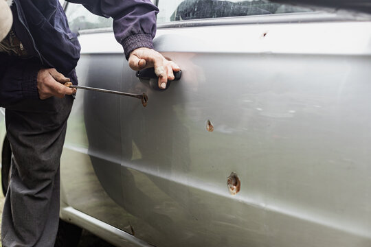 Part Of A Gray Car Damaged By Fragments From Military Missiles, A Mechanic Is Working On A Fix, Ukrainian War