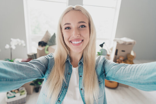 Photo of cute cheerful young lady dressed denim shirt tacking selfie moving new home indoors apartment