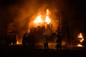 Firefighters standing in front of burning transformer after the missile attack in Ukraine