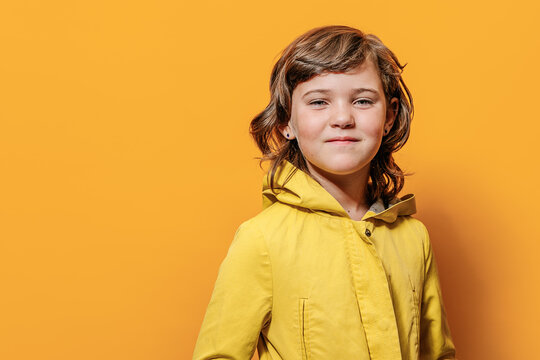 Girl looking at camera against yellow wall in studio