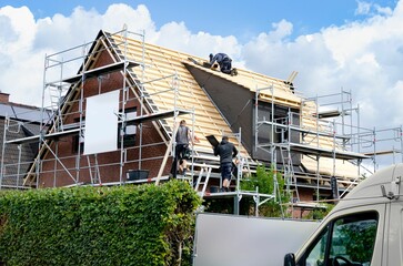 Roofers during the roof renewal © Marek Romanowski/Wirestock Creators
