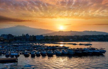 picturesque sunrise or sunset in a sea port with a gulf dock pier with tour boats and a town with cloudy sky on background of a seashore landscape