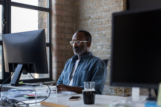 African American businessman sitting at desk in an office working on a computer