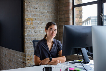 Portrait of young businesswoman working at a desktop computer in an office