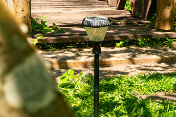 Daytime view of led lighting solar cells lamp at small wooden bridge near granite slab pathway at a...