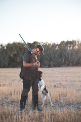 A hunter caresses his dog after hunting.