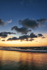 Obraz premium Beautiful sunset sunrise at the beach with dramatic clouds in the blue purple yellow sky over the sea - Bali