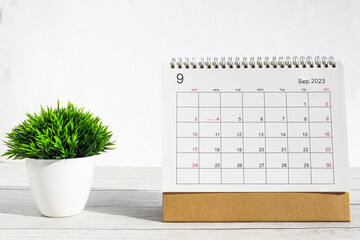 September 2023 Desktop calendar for planners and reminders on wooden table with plant pots on a white background. - obrazy, fototapety, plakaty