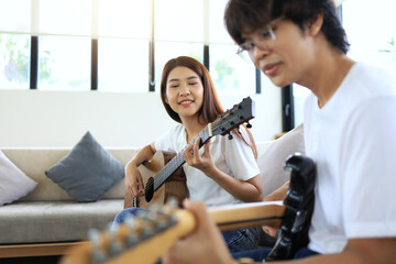 A woman and a man play guitar together as a guitar jam with an acoustic guitar and an electric...