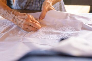 Obraz na płótnie Canvas Closeup on the hands of a seamstress assembling an embroidered guayabera shirt