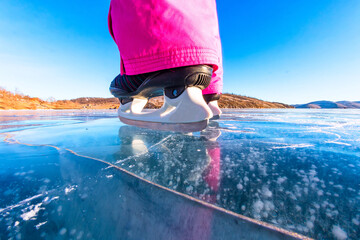 Feet close-ups of skates on legs A brightly colored dressed woman on the blue ice of Lake Baikal