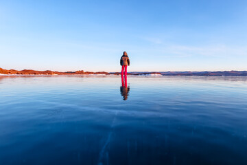 Girl walking on cracked ice of a frozen lake Baikal