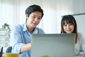 Two young business colleague discussing online information, working together in corporate office.