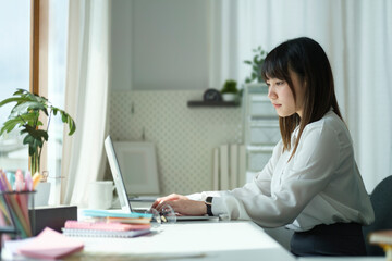 Concentrated start up business woman working on project with laptop at comfortable workplace.