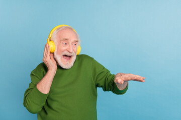 Photo of overjoyed carefree funny granddad arm touch headphones enjoy sound isolated on blue color...