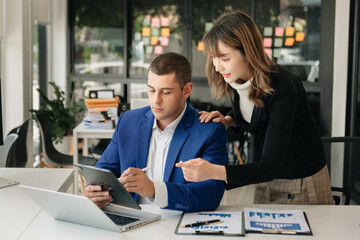 Kind leader executive manager share and discuss business solutions plan ideas on tablet with Asian female marketing manager in modern office..