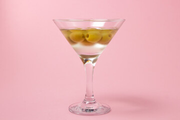 Martini glass with olives on a pink background. Delicious alcoholic drink.