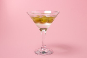 Martini glass with olives on a pink background. Delicious alcoholic drink.