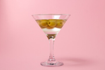 Martini glass with olives on a pink background. Delicious alcoholic drink.