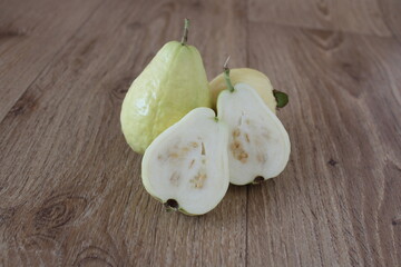 Cut fresh white guava on wooden table. Delicious and juicy fruit. Close up, sitting view.