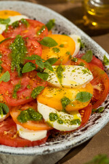 Close up of Caprese salad with yellow and red tomato on browm background. Italian cuisine.