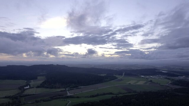 Aerial time lapse shot of forests and meadows of plateau region Baar between Black Forest and Swabian Alps on a cloudy evening in late summer seen from hill &bdquo;Hohenlupfen&ldquo;