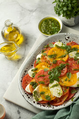 Close up of Caprese salad with yellow and red tomato on browm background. Italian cuisine.