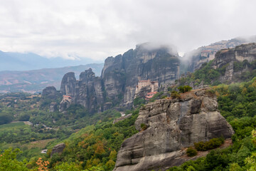 Scenic view of Holy Monastery of St Nicholas Anapafsas and Holy Monastery of Rousanos surrounded by fog on cloudy day, Kalambaka, Meteora, Thessaly, Greece, Europe. Landmark build on rock formations