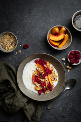 Petit déjeuner bol de muesli yaourt nectarines pêches noisettes et framboises
