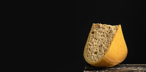 french hard cheese with holes emmentaler on a dark background. Long banner format