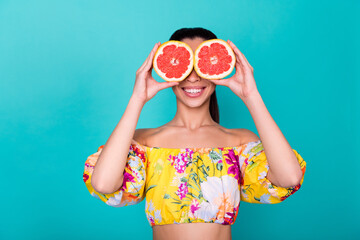 Portrait of attractive cheerful korean girl closing eyes with grapefruit grimacing isolated on cyan color background