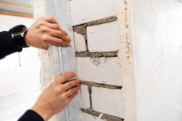 Checking the evenness of the walls in the built house. Examination of construction work and the quality of performance of the contractor. Close-up. unrecognizable person